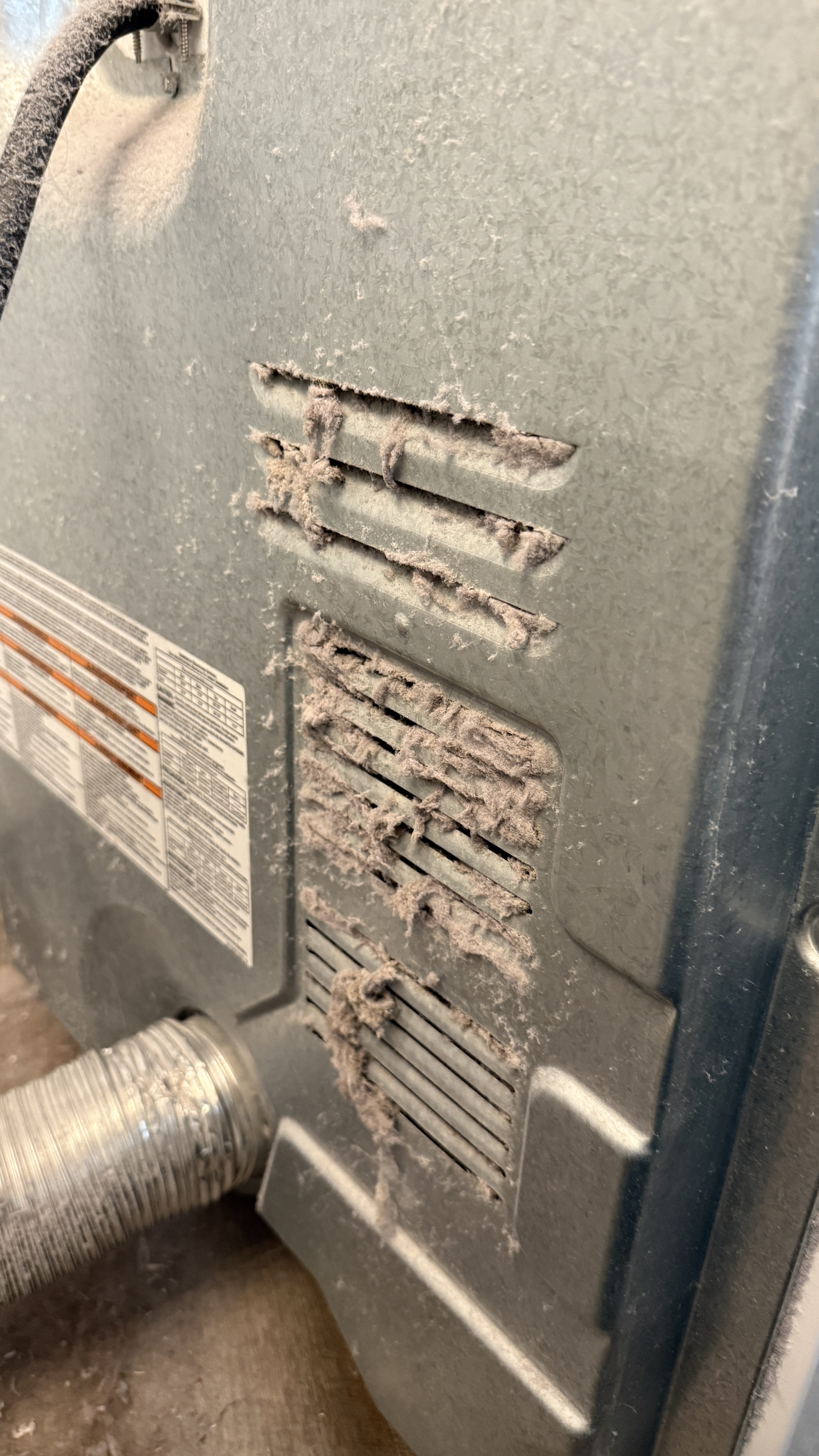 Back of a Whirlpool dryer with intake louvers completely clogged with lint and dust