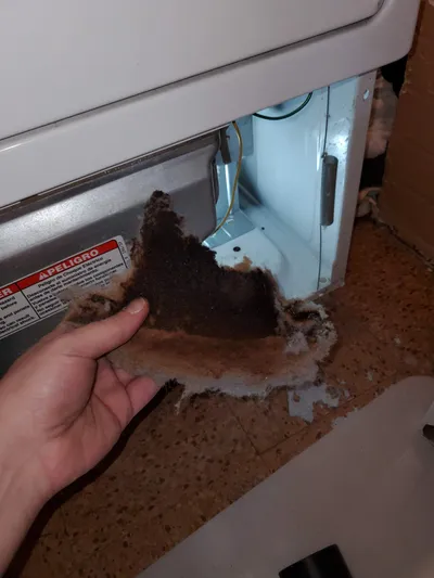 Burnt lint buildup inside a dryer near heat sources
