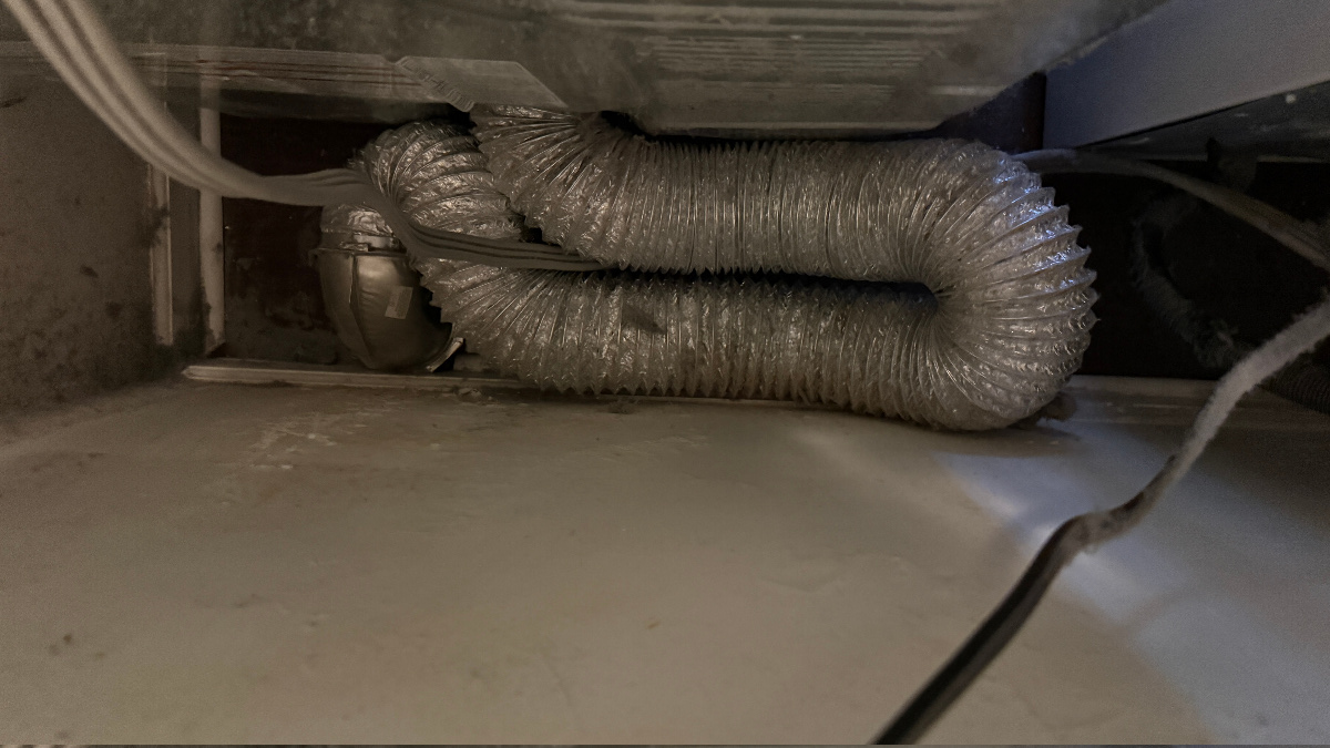 Tangled, kinked dryer transition hose restricting airflow behind dryer