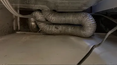 Tangled, kinked dryer transition hose restricting airflow behind dryer