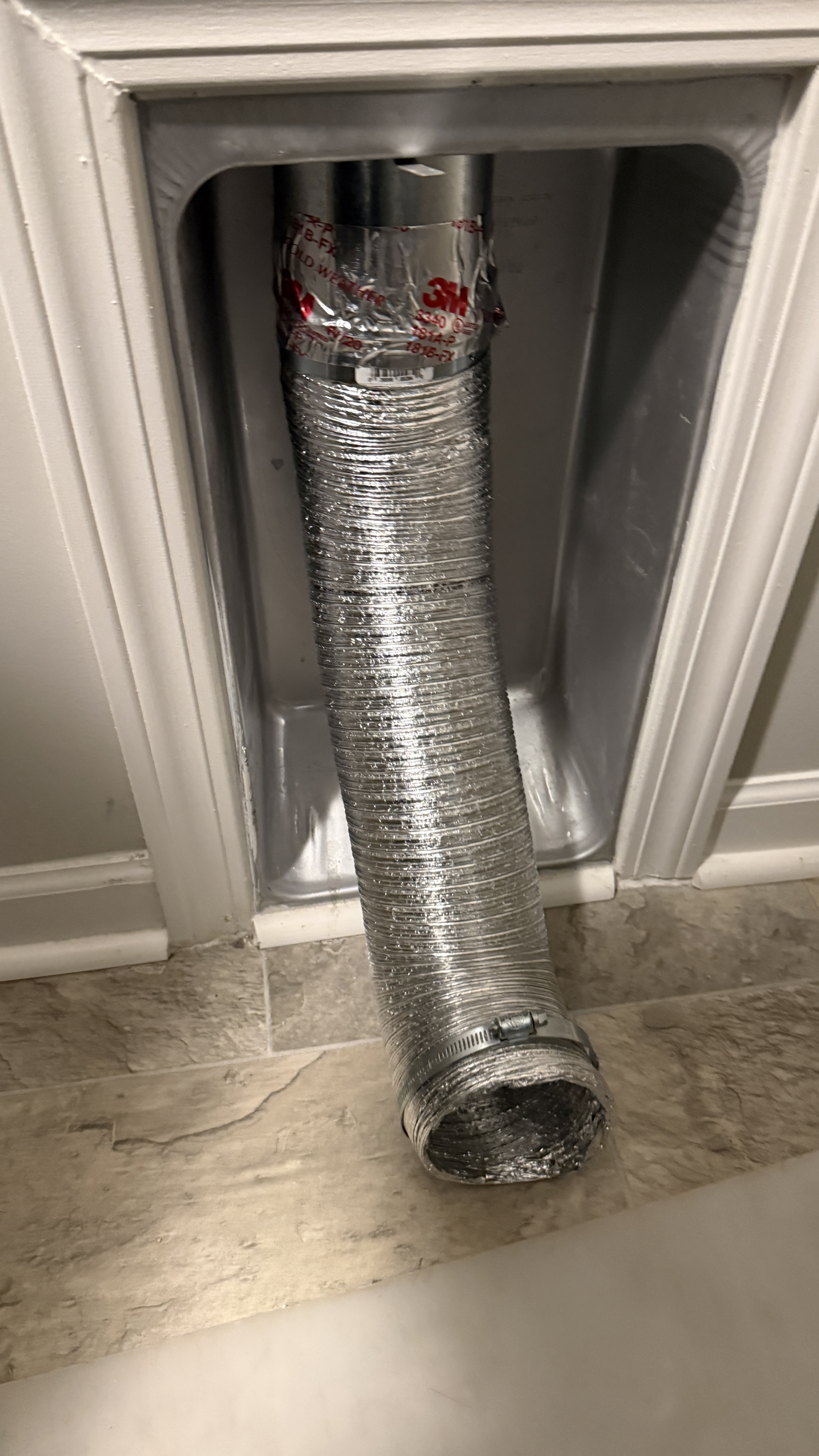 DryerFlex duct sealed with foil tape at wall connection in recessed dryer vent box