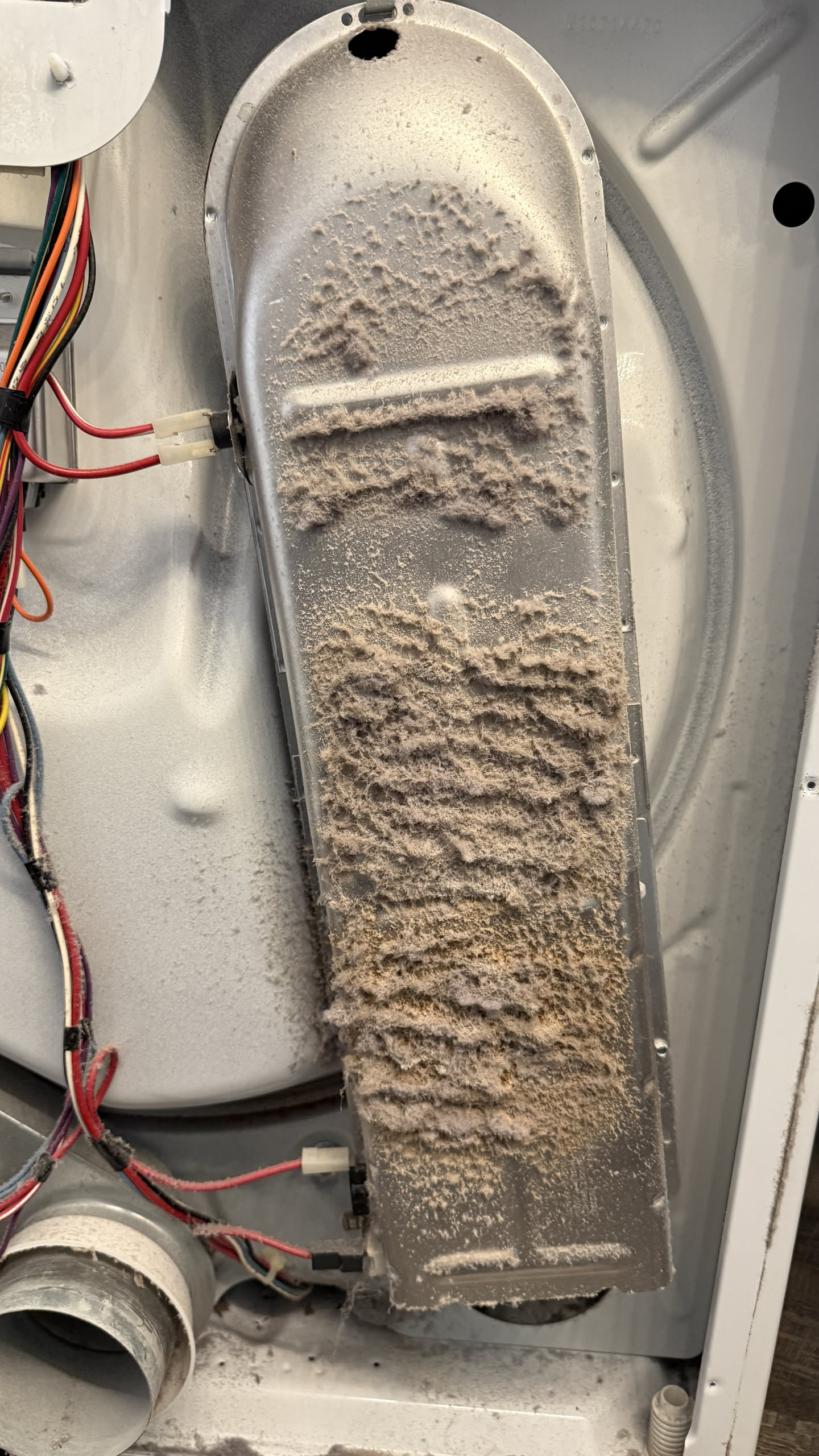 Dryer heater assembly coated in scorched lint after a clogged vent caused heat to back up into the cabinet