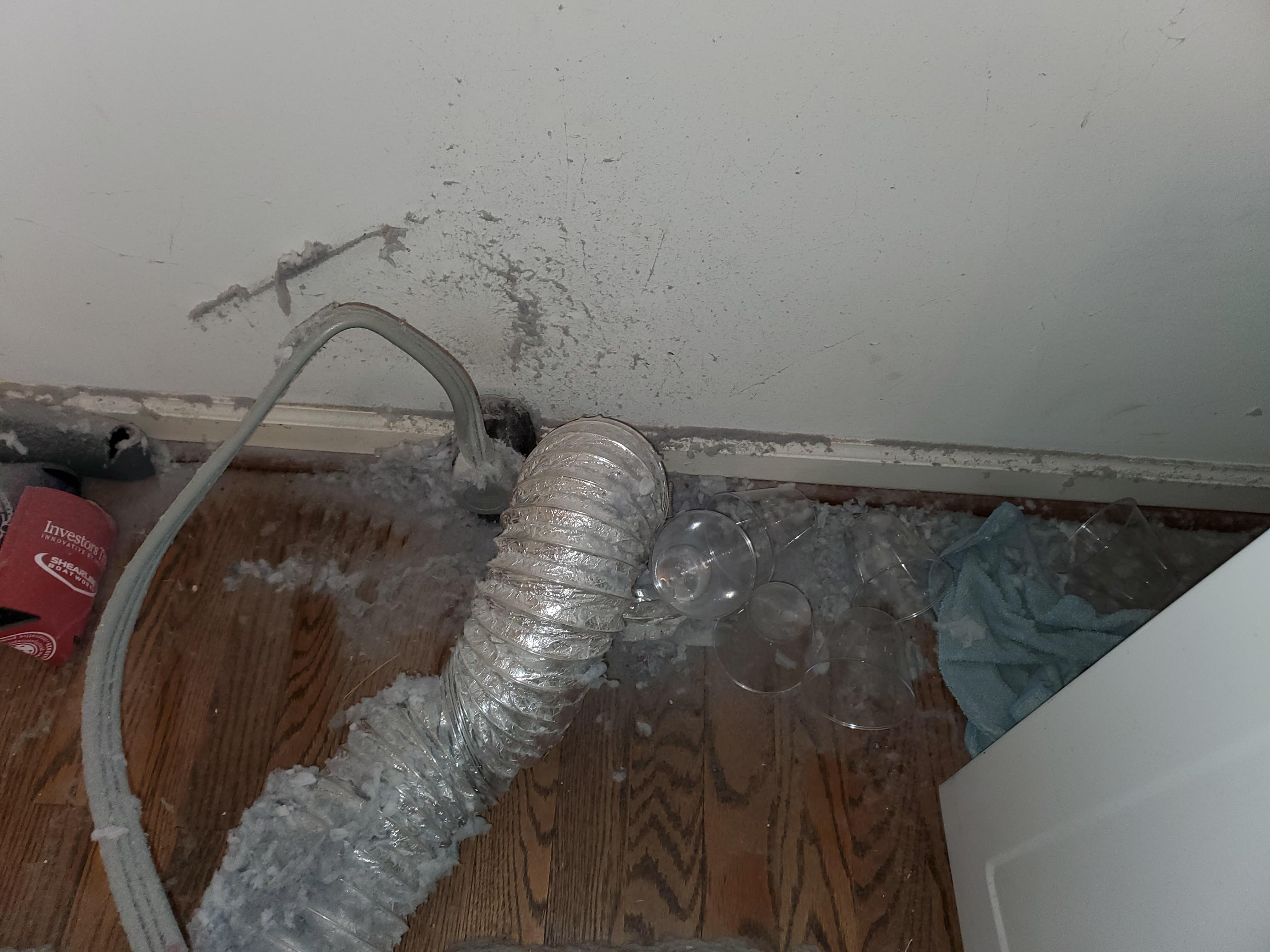 Dryer lint accumulated near the 240-volt dryer plug behind the appliance