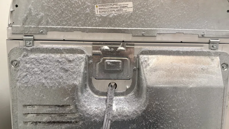 Lint and dust accumulated on the floor and wall behind a clothes dryer