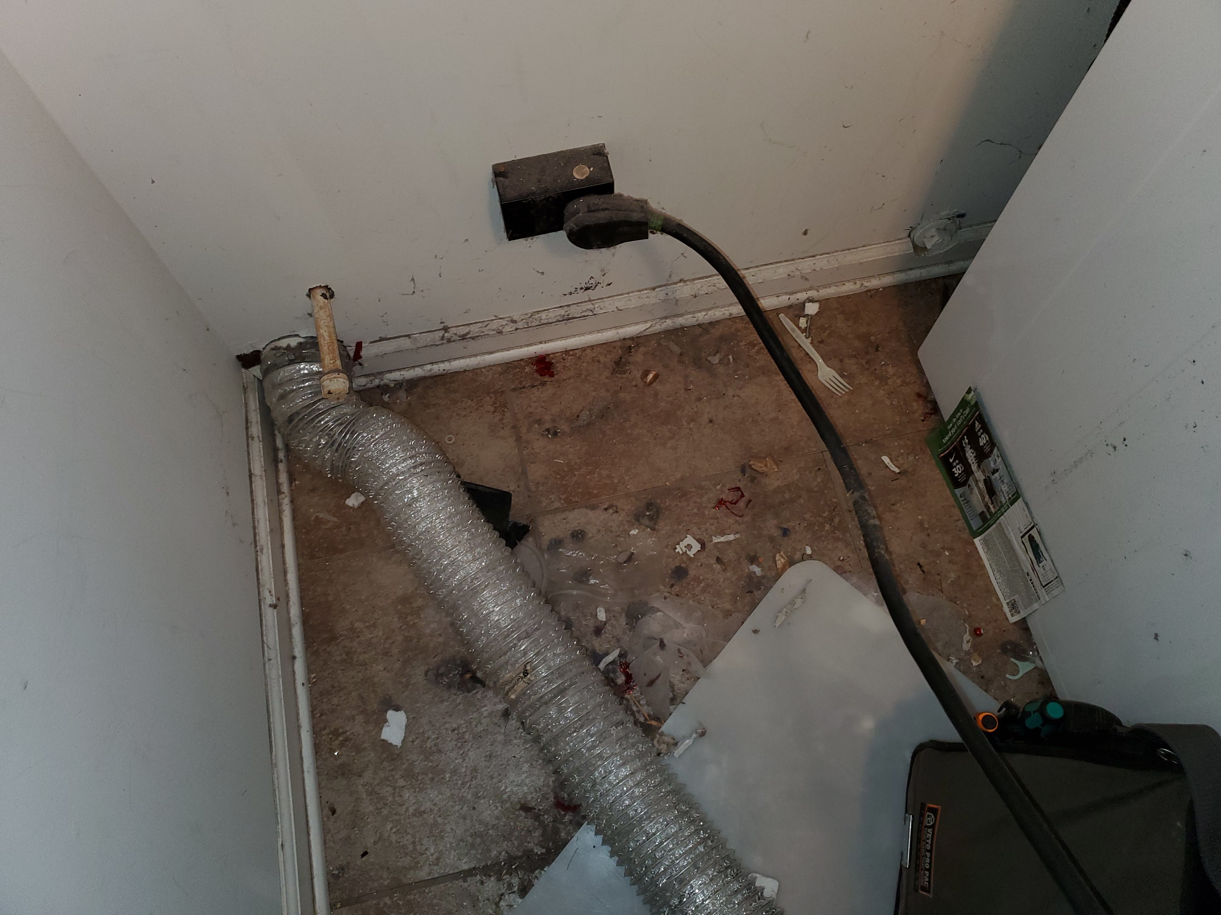 Messy laundry area behind dryer with poor vent hookup and dust