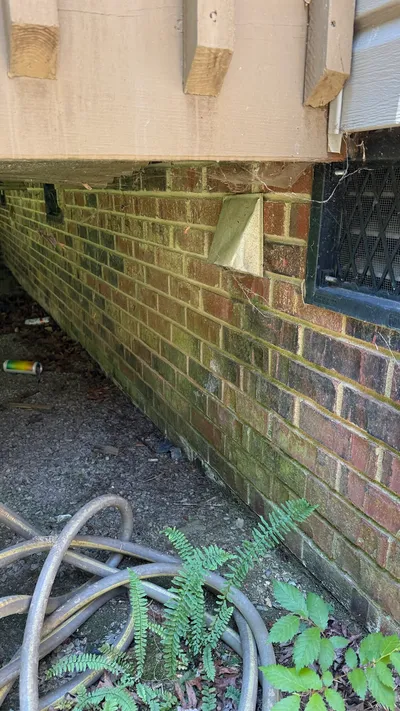 Old restrictive 70s dryer vent cover under a deck in New Irving Park Greensboro
