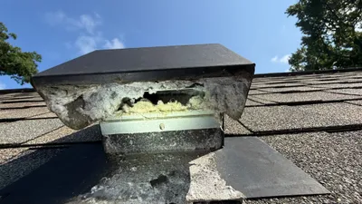 Packed metal dryer vent cover on a west Greensboro roof