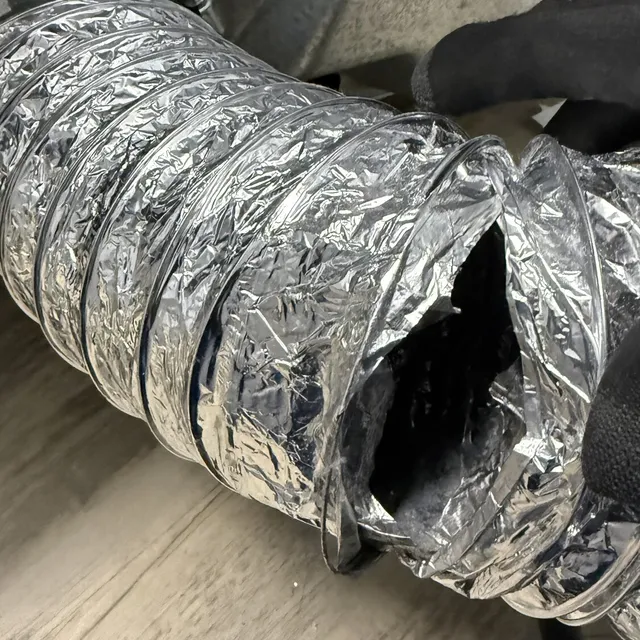 Ripped dryer transition hose blowing dust into a Waterbury laundry room