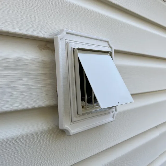 Metal dryer vent cover with bird-guard insert on vinyl siding in Coble Farm Greensboro