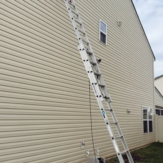 Tall ladder up to a second story dryer vent on a vinyl sided home in Reedy Fork Ranch